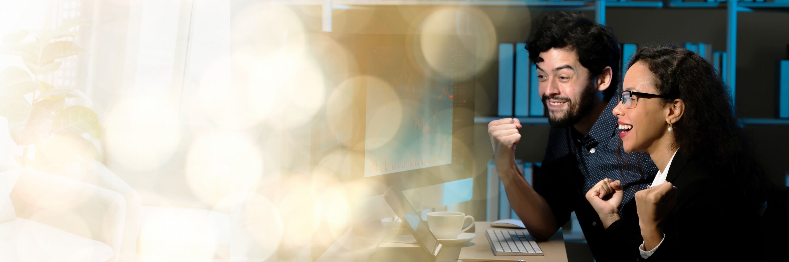 Twee collega’s vieren een positief financieel resultaat achter een computer